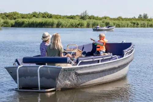 Gezelschap met kind en zwemvest aan boord van een sloep met buitenboordmotor