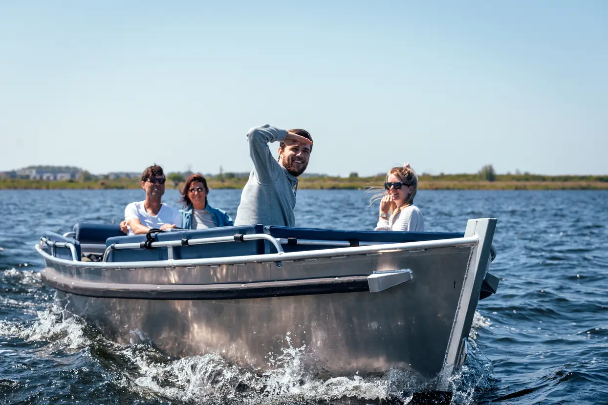 Kapitein wijst enthousiast een route aan vanaf een sloep op het water in Almere